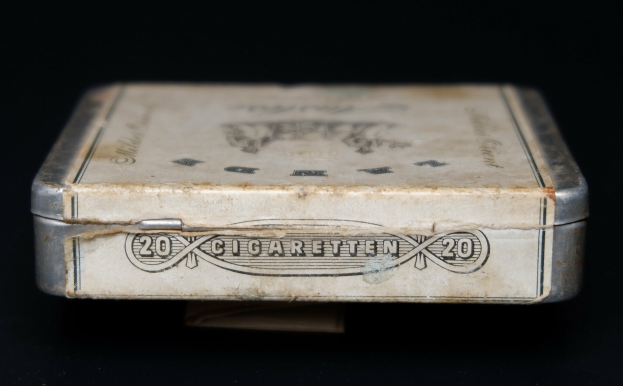 Alte Metall-Zigaretten-Dose mit vintage-Text auf einem schwarzen Tisch.