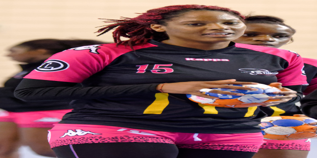 Eine Gruppe von Frauen, die zusammenstehen und jeweils einen Fußball halten, wobei die Frau in der Mitte ein menschliches Gesicht hat und direkt in die Kamera schaut, trägt ein weißes T-Shirt und blaue Shorts.