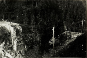Ein Schwarz-Weiß-Foto einer Brücke über einem Fluss mit Bäumen, Pfählen und Felsen im Hintergrund, mit dem Text "1930er-Jahre-Bau der Brücke" unten.