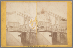 Ein altes Foto einer Brücke unter Reparatur, die über ein Gewässer verläuft, mit verstreuten Werkzeugen und Materialien und Gebäuden im Hintergrund.