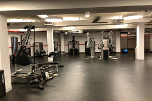 Ein Gymnastikboden mit Trainingsgeräten, darunter ein Ball, Säulen und Deckenleuchten sowie zusätzliche verstreute Gegenstände.