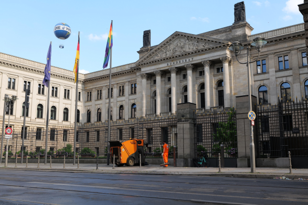 Großes modernes Gebäude mit vielen Fenstern, als Bundestag in Berlin, Deutschland identifiziert, umgeben von Straßeninfrastruktur und Passanten unter einem bewölktem Himmel.