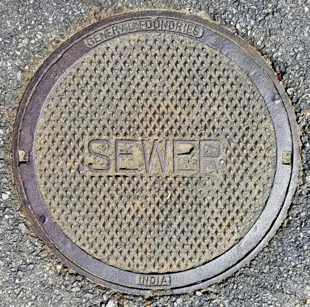 Metallschachtdeckel auf einer Straße mit der eingravierten Aufschrift "Kanal"