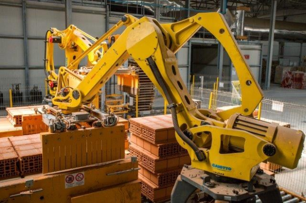 Großes Industrie-Lager mit gestapelten Kisten, Kränen, Zaun, Pfosten und einer fernen Wand in einer Fertigungsumgebung.