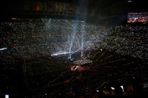 Gro├če Menschenmenge in hell erleuchtetem Stadion bei Nacht mit einem Bildschirm, der rechts die Ergebnisse der Super Bowl XLVII-Halbzeitshow anzeigt.