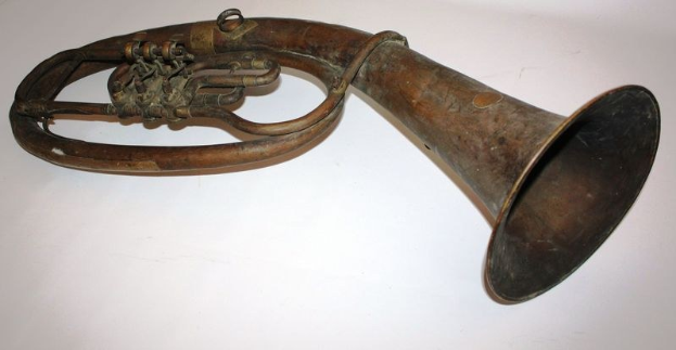 Altes Messinghorn mit glänzender Oberfläche, gebogener Hals und aufgeblähtem Trichter, verziert mit kunstvollen Gravuren, auf einem weißen Hintergrund.