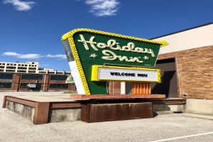 Holiday Inn Schilder auf der Seite eines Gebäudes mit einem freistehenden Schild davor.