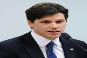 Ein Mann im Anzug spricht in ein Mikrofon an einem Rednerpult, wahrscheinlich zur Vorstellung eines Gesetzesentwurfs zum Verbot des Internets.