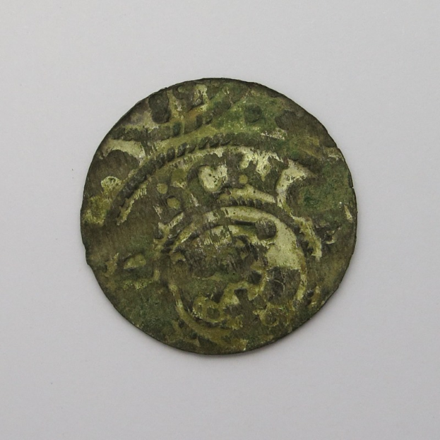 Eine grüne Münze mit einem kreisförmigen Design auf einem weißen Hintergrund.