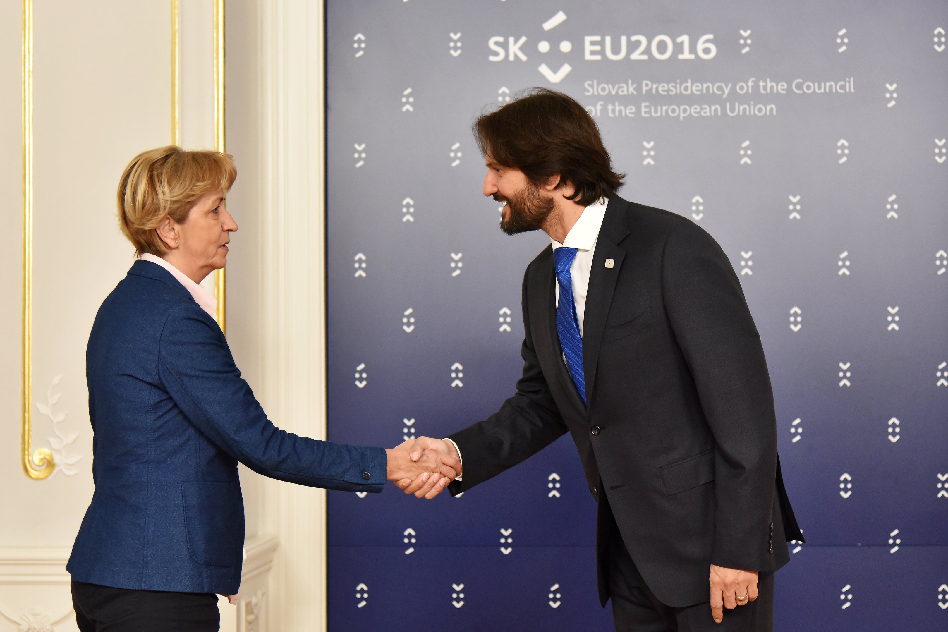 Bundeskanzlerin Angela Merkel und Bundespräsident Joachim Gauck schütteln sich die Hand und lächeln vor einem Banner mit der Aufschrift "EU-Gipfel"