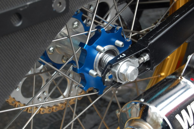 Ein Motorradrad und ein Schalldämpfer sind im Bild zu sehen.