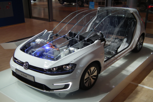 Ein weißer Volkswagen e-Golf-Elektroauto auf der IAA in Frankfurt, umgeben von Glastüren und anderen Fahrzeugen im Hintergrund.