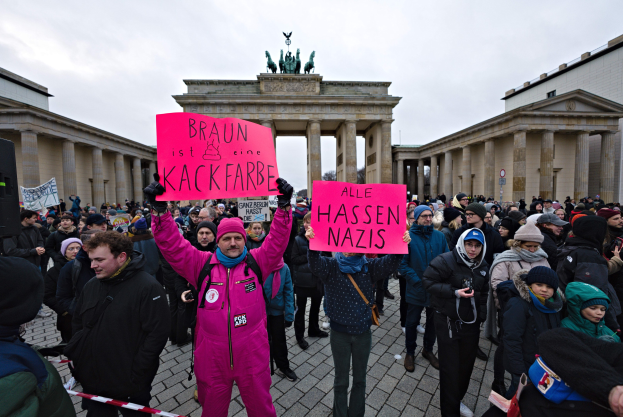 Eine Gruppe von Menschen demonstriert vor dem Brandenburger Tor in Berlin und hält Schilder gegen die anti-nazistische Bewegung der deutschen Regierung.