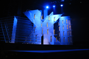 Bühne für eine Preisverleihung mit dunklem Hintergrund und minimaler Beleuchtung, mit ein paar Gegenständen, die wahrscheinlich mit dem Event zu tun haben.